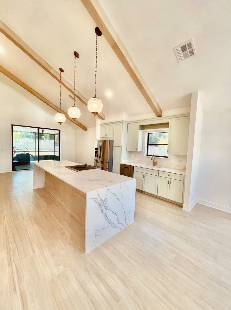 Custom home finishings — vaulted beam ceiling, waterfall quartz island and custom cabinetry in a St. Johns County, FL kitchen