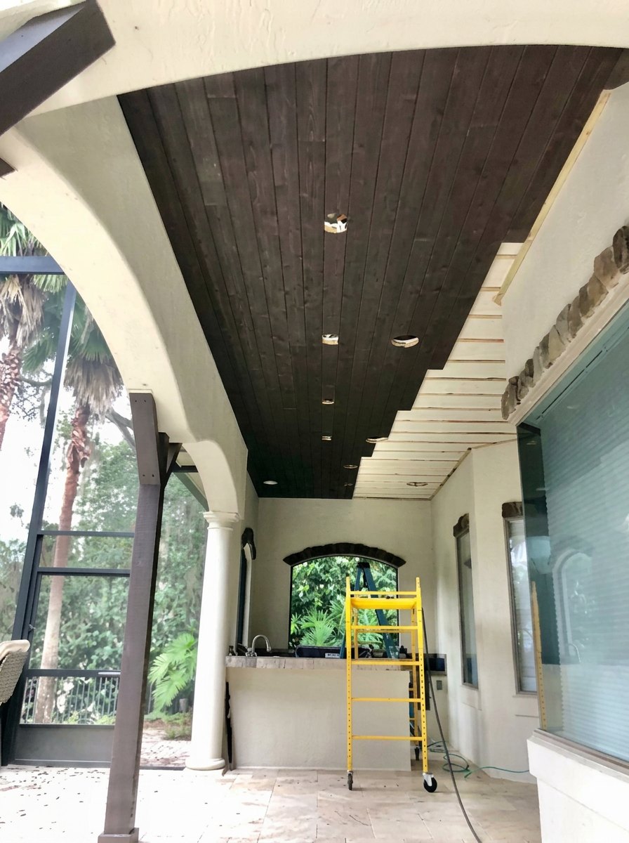 Custom stained tongue-and-groove wood ceiling carpentry on a covered lanai in St. Johns County, FL